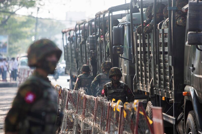Soldiers stand next to military vehicles as people gather to protest against the military coup, in Yangon, Myanmar, February 15, 2021.  Reuters