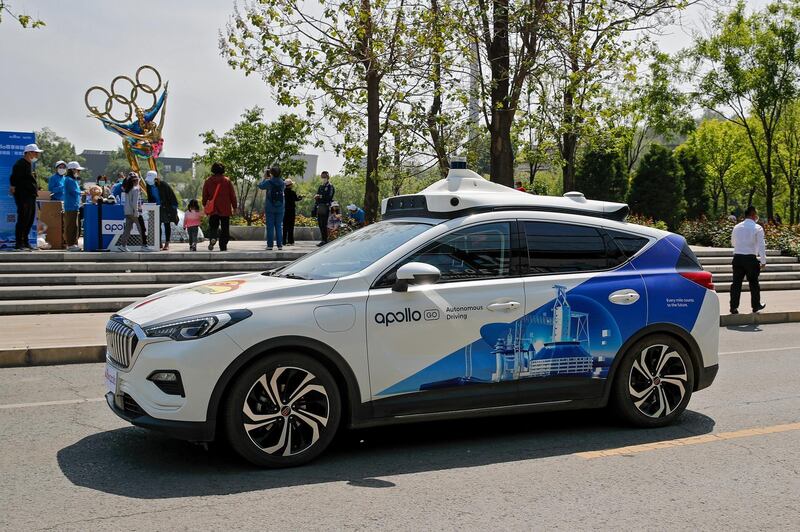 A Baidu Apollo Robotaxi passes its customer service counter setup at the Shougang Park in Beijing, Sunday, May 2, 2021. Chinese tech giant Baidu rolled out its paid driverless taxi service on Sunday, making it the first company that commercialized autonomous driving operations in China. (AP Photo/Andy Wong)