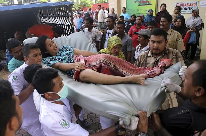 Hospital workers and family members carry a woman injured in the earthquake. Heri Juanda / AP Photo