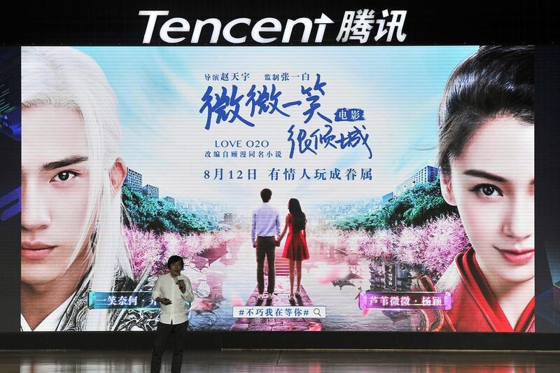 A visitor stands in front of an advert for Tencent in Fuzhou city, south-east China's Fujian province. Mobile games helped the tech juggernaut boost its earnings by 43 per cent. 