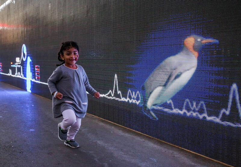 Abu Dhabi, United Arab Emirates, December 31, 2017.   New Year's Eve At the Abu Dhabi New Year's Eve Village.  A little girl races agains a Digital Penguin at the Running Wall.
Victor Besa for The National.
National
Reporter:  John Dennehy