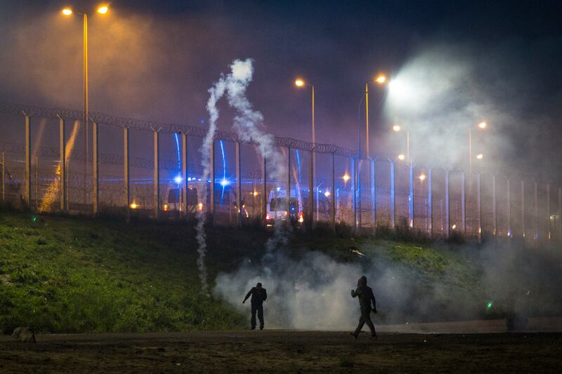 Migrants return a smoke grenade as they clash with French riot police in October 2016