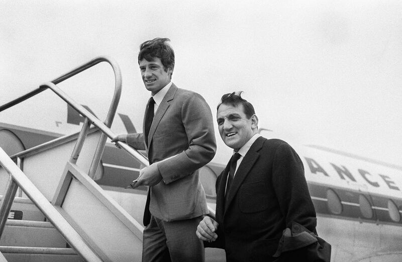 In this photo taken on September 13, 1963, French actors Lino Ventura, right, and Jean-Paul Belmondo board a plane for Casablanca, Morocco, to attend the shooting of the film '100 000 dollars au soleil (Greed in the Sun)'. Belmondo has died at the age of 88, it was announced on September 6, 2021. AFP