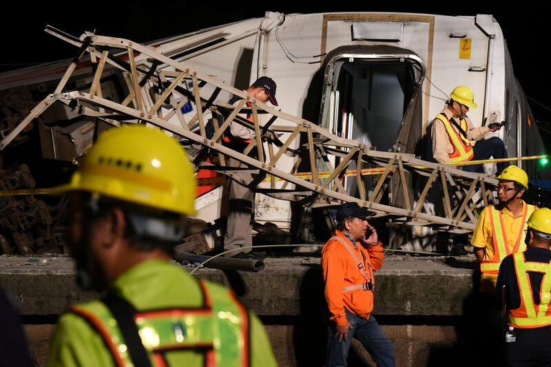 Workers walk around derailed train as they prepare to clear the accident site, in Yilan, Taiwan. REUTERS