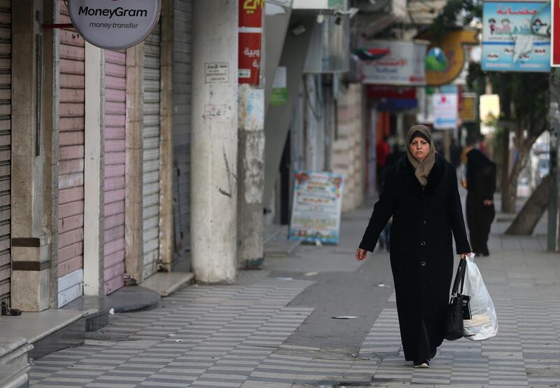 A Palestinian woman walks past closed shops in Gaza City during a strike in protest against the siege on Gaza and the economic situation, on January 22, 2018. (Photo by MOHAMMED ABED / AFP)