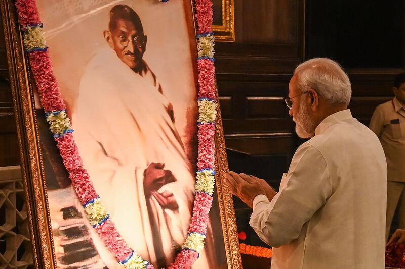 India's Prime Minister Narendra Modi gestures beside a portrait of Indian independence icon Mahatma Gandhi at Parliament House in New Delhi on October 2, 2019 to mark Gandhi's 150th birth anniversary.  / AFP / Money SHARMA
