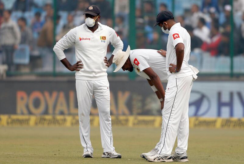 Sri Lanka's Suranga Lakmal, centre, vomits as his teammates stand next to him during the fourth day of their third test cricket match against India in New Delhi. Altaf Qadri / AP Photo