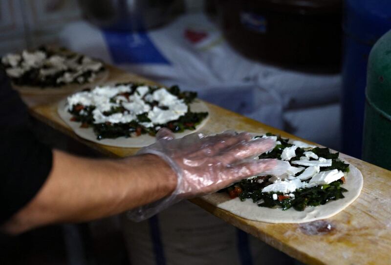 Cheese and leafy vegetables are added to the flattened dough. AFP