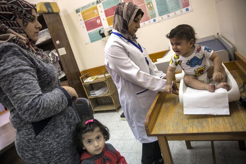 Sahar Sweila with her son Bara'a,11-months old and daughter Joud, 3 years old as her son is weighed during his  appointment at the Ard El Insan Child Nutrition Center in Gaza City,Gaza on November 28,2018. The Gaza based organisation treats malnutrition,anemia and other conditions . It also tries to teach nutrition to the mothers.
(Photo by Heidi Levine for The National).