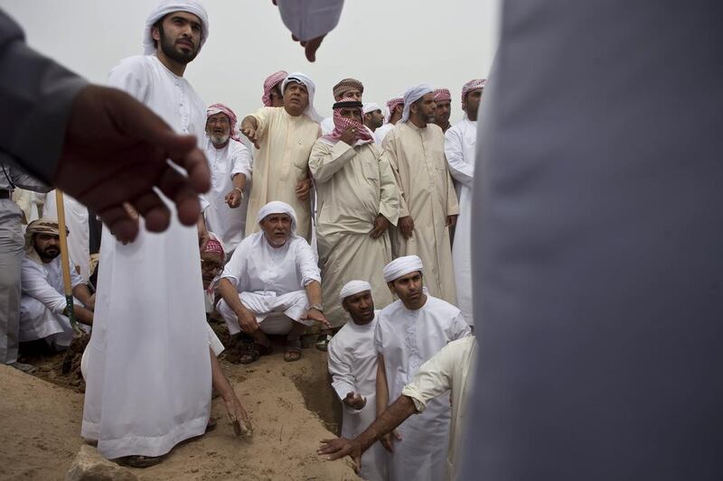 Family members and members of the community wait to lower the body of Emirati police officer Tariq Al Shehi into his grave at the Sha'am grave yard in Ras Al Khaimah. Antonie Robertson / The National