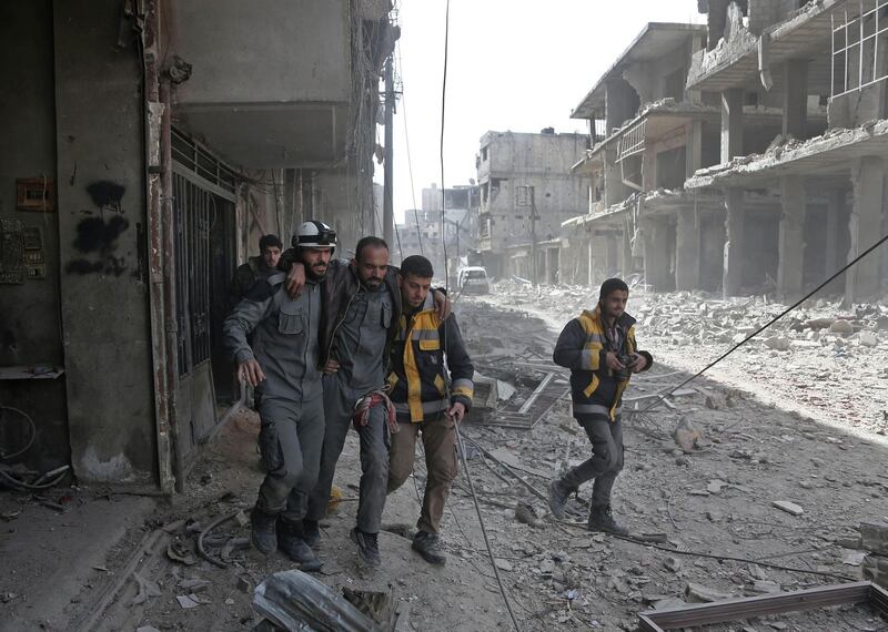 Volunteers from the Syrian civil defence help a man in Hamouria during Syrian government shelling on rebel-held areas in the Eastern Ghouta region on the outskirts of the capital Damascus on March 6, 2018. Abdulmonam Eassa / AFP