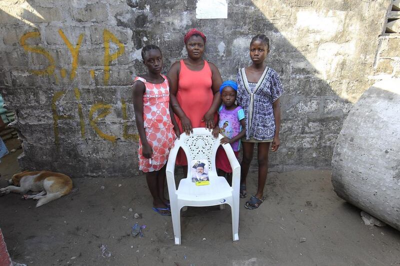 Rachael Fayia, centre, and her children Binta Jalloh, left, Fatmata Jalloh, right, Naomi Dee, second right, pose for a family portrait at their home in West Point, Monrovia, Liberia. The empty chair symbolises Rachael’s husband, who died of the Ebola virus during an outbreak of the disease in 2014. Ahmed Jallanzo / EPA