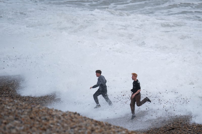 Two men play amongst the breakers on Chiswell Beach in Dorset