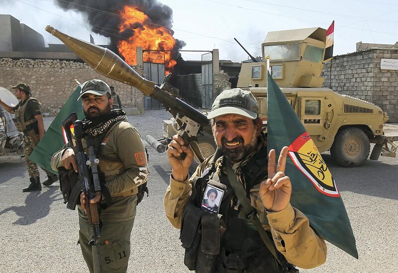 Fighters of Hashed Al-Shaabi (Popular Mobilization units) flash the victory gesture as they advance through a street in the town of Tal Afar, west of Mosul, after the Iraqi government announced the launch of the operation to retake it from Islamic State (IS) group control, on August 26, 2017. (Photo by AHMAD AL-RUBAYE / AFP)