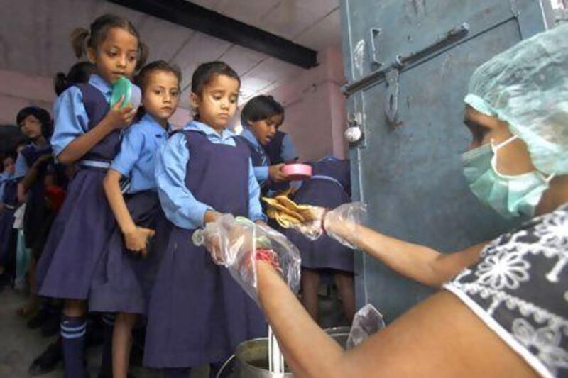 Schoolgirls collect free midday meals at government-run primary school in New Delhi. India may soon pass a new law to give millions more people cheap food. Mansi Thapliyal / Reuters