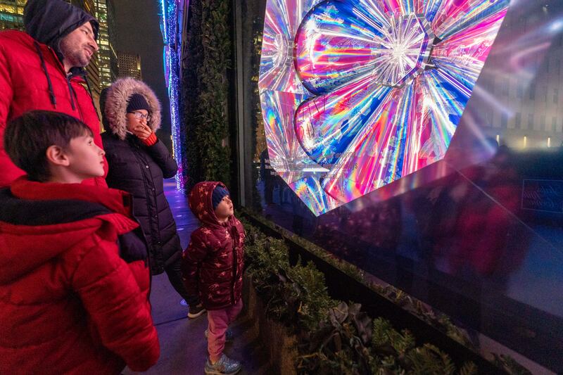 A family takes in the holiday window display at Saks Fifth Avenue in New York. AP