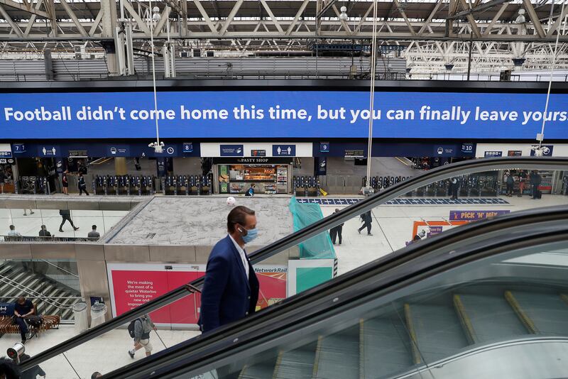 Commuters walk past an advertising board referring to the Euro 2020 final result, in Waterloo station, London. British Prime Minister Boris Johnson is set to confirm that all remaining lockdown restrictions in England will be lifted in a week’s time.