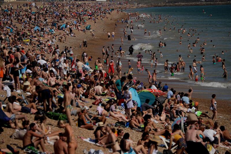 On Britain's hottest day of the year so far with temperatures reaching 32.6 degrees Celsius (90 degrees Fahrenheit) at Heathrow airport, people relax on Brighton Beach in Brighton, England, Wednesday, June 24, 2020. The government announced Tuesday that from July 4 social-distancing rules will be relaxed. People will be advised to stay at least 1 meter (3 feet) apart from others, rather than requiring 2 meters - as long as they take other measures to reduce transmission of the virus, such as wearing a mask in enclosed spaces. (AP Photo/Matt Dunham)