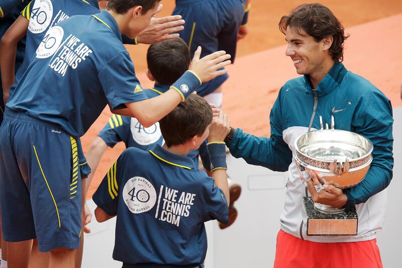 Rafael Nadal of Spain holds his trophy as he shakes hands with ball boys after defeating compatriot David Ferrer in their men's singles final match to win the French Open tennis tournament at the Roland Garros stadium in Paris June 9, 2013. Nadal made light work of fellow Spaniard Ferrer to win a protest-interrupted French Open final 6-3 6-2 6-3 on Sunday and become the first man to win eight singles titles at the same tournament.      REUTERS/Philippe Wojazer (FRANCE  - Tags: SPORT TENNIS)   *** Local Caption ***  RGT911_TENNIS-OPEN-_0609_11.JPG