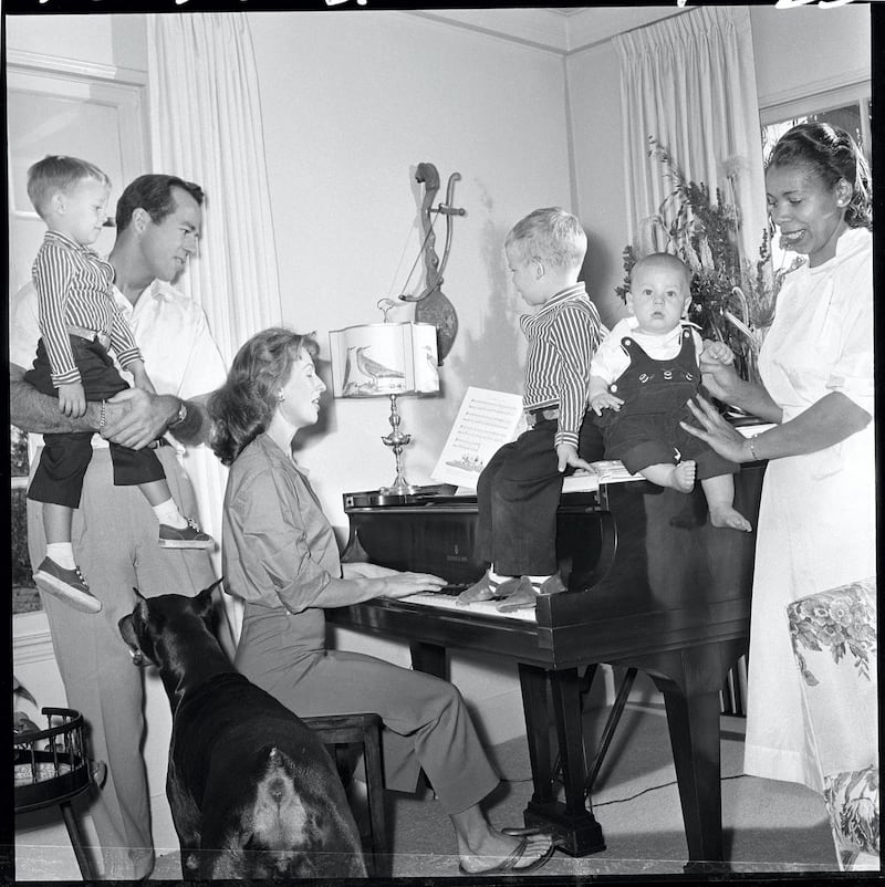 LOS ANGELES - OCTOBER 29: Cloris Leachman (at piano) with her husband, George Englund (an MGM Producer). George holds son Adam (just 4 years old). Son Bryan (age 2) and George Jr. (5-months) sit on piano. Julia Harris is the children's nurse. Family pet, a Doberman pinscher named Gabby. The two-story Spanish-style home in is fashionable West Los Angeles. Image dated October 29, 1957. (Photo by CBS via Getty Images) 
