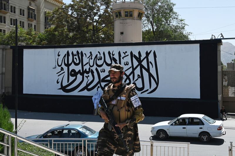 A Taliban fighter patrols outside the US embassy in Kabul, where the Taliban flag hangs on an outer blast wall. AFP