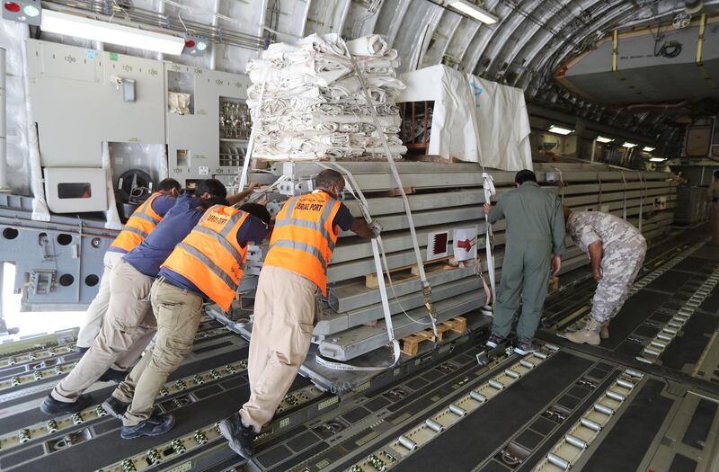 Workers load a plane as Qatar begins sending field hospitals and medical aid to Lebanon from the al-Udeid airbase on August 5, 2020 on the outskirts of Doha. - Rescuers searched for survivors in Beirut today after a cataclysmic explosion at the port sowed devastation across entire neighbourhoods, killing more than 100 people, wounding thousands and plunging Lebanon deeper into crisis. (Photo by KARIM JAAFAR / AFP)