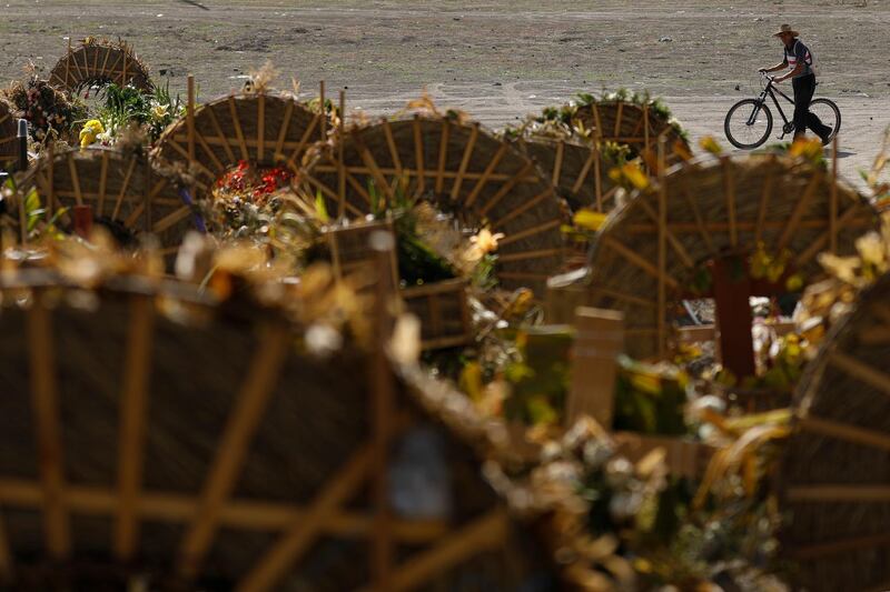 Gravedigger Martin Niano pushes his cycle past wreaths adorning recent graves in a section of the Municipal Cemetery of Valle de Chalco on the outskirts of Mexico City. AP Photo