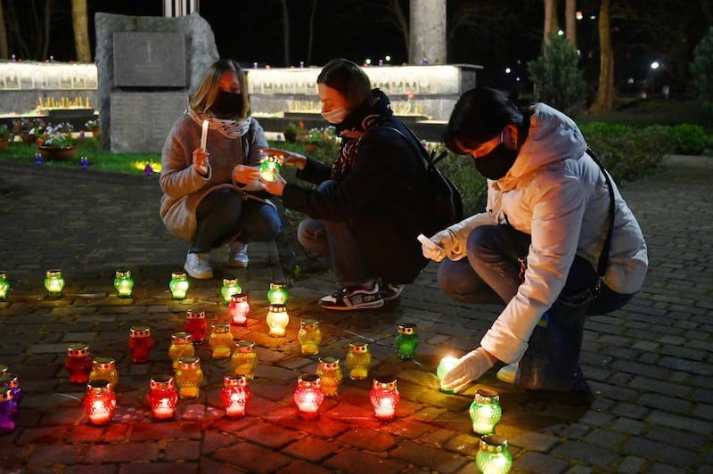 Women wearing face masks light candles at the monument to Chernobyl victims in Slavutich.  AFP