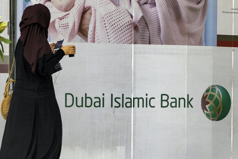 A pedestrian checks her smartphone while passing a Dubai Islamic Bank PJSC bank branch in Dubai, United Arab Emirates, on Tuesday, Sept. 4, 2018. Abu Dhabi is engineering a second bank merger in its latest attempt to stay competitive in the era of lower oil prices. Photographer: Christopher Pike/Bloomberg