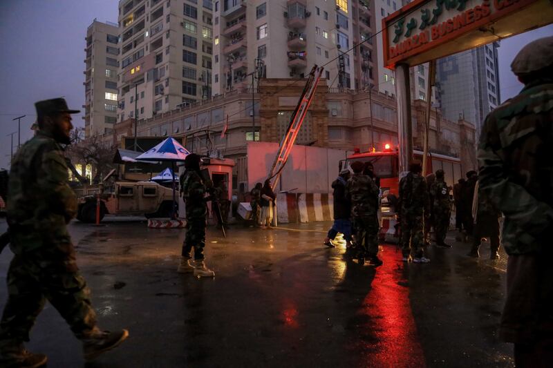 Taliban fighters stand guard at the scene of the bomb blast. EPA