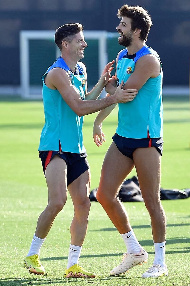 Robert Lewandowski and Gerard Pique joke during a training session. AFP