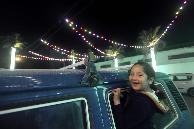 A Palestinian girl leans out from the window of a vehicle to see the decorative lights in Gaza City as the threat of the COVID-19 pandemic lingers ahead of the Muslim holy month of Ramadan.  AFP