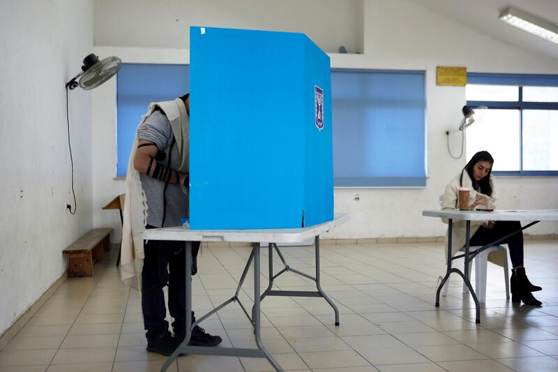 A man stands behind a booth at a polling station in Nokdim, in the occupied West Bank. Reuters