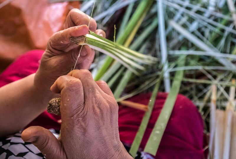 A woman uses thread to slice papyrus into thin strips.