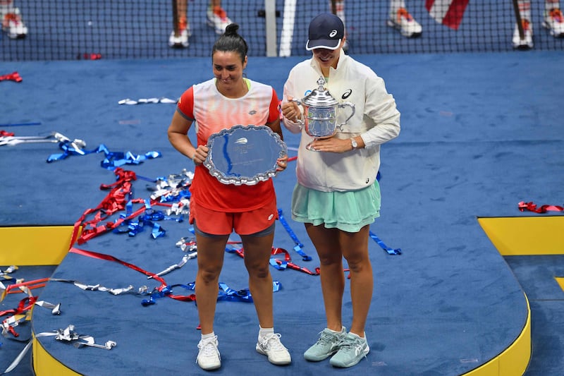 Iga Swiatek and Ons Jabeur pose for photos during the trophy ceremony following their US Open final match. AFP