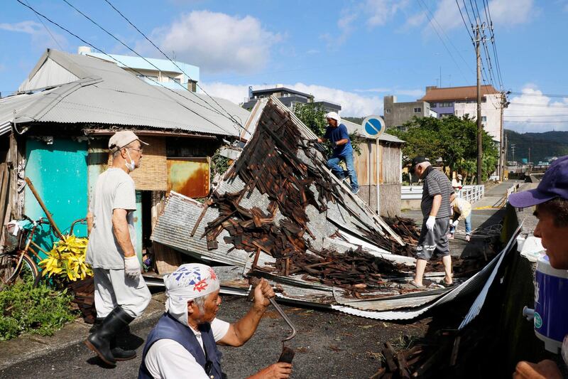 Residents mend the roof broken by strong wind following a typhoon in Amami, Kagoshima prefecture, southwestern Japan.  AP