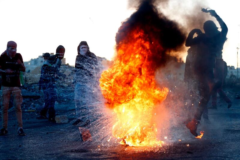 A Palestinian demonstrator kicks a burning tire during clashes with Israeli forces near a checkpoint in the West Bank city of Ramallah. Abbas Momani / AFP Photo