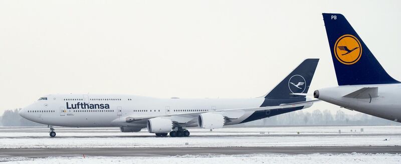 A Boeing 747-800 (L) displaying the new logo of the German airline Lufthansa is seen behind the tail of a plane displaying the old logo of the airline at the Airport in Munich, southern Germany on February 8, 2018. (Photo by Chiara PUZZO / dpa / AFP) / Germany OUT