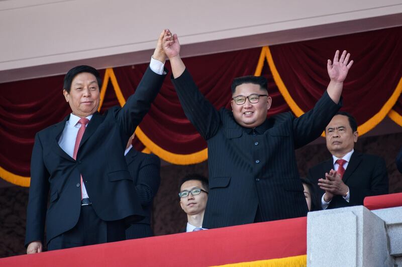 North Korea's leader Kim Jong Un, right, waves with China's Chairman of the Standing Committee of the National People's Congress Li Zhanshu, left, from a balcony of the Grand People's House on Kim Il Sung square following military parade and mass rally - North Korea was marking the 70th anniversary of its founding.  AFP