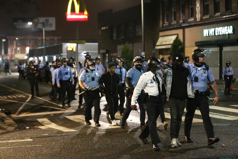 Police lead several people in handcuffs to a police van on 52nd Street in West Philadelphia. AP