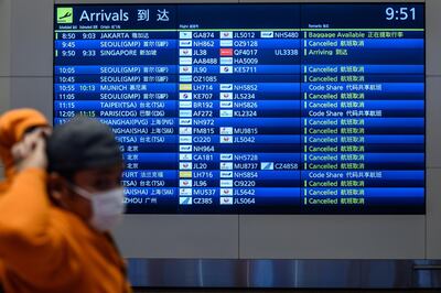 An arrival board showing cancelled flights is seen past a mask-clad man at Tokyo's Haneda Airport on March 10, 2020. The death toll from the COVID-19 illness caused by the novel coronavirus neared 4,000, with more than 110,000 cases recorded in over 100 countries since the epidemic erupted in December in Wuhan, China. It has disrupted global travel, and cancelled conferences and sporting events.
 / AFP / Philip FONG
