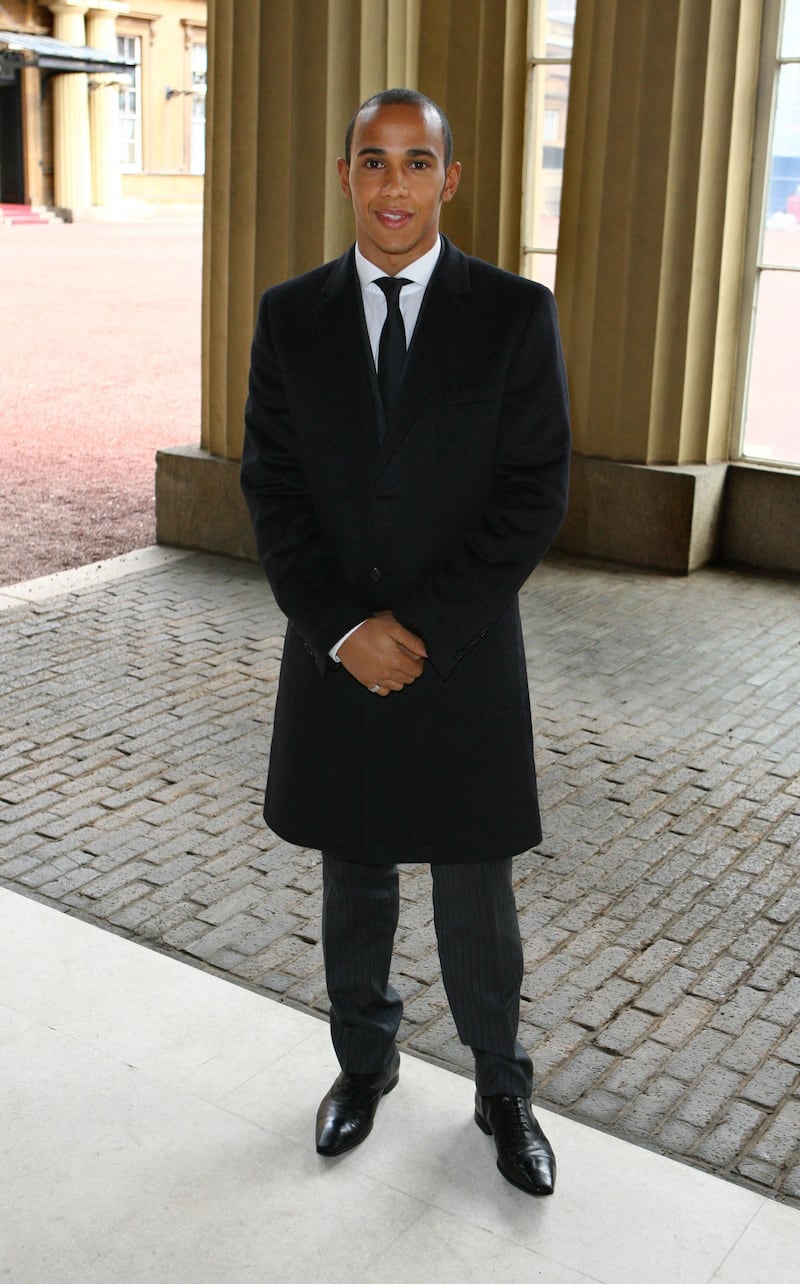 Lewis Hamilton, in a black coat and suit, arrives at Buckingham Palace to be awarded an MBE by Queen Elizabeth II, on March 10, 2009, in London. WPA