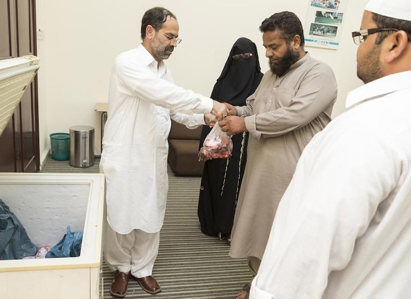 Asad Ullah Khan from the Pakistan Association Dubai hands out sacrificial meat at the Oud Metha headquarters. Antonie Robertson / The National