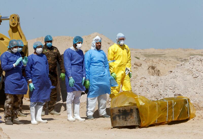 Iraqi Shiite volunteers from Hashid Shaabi (Popular Mobilization Forces) and members of a medical team wearing protective suits, pray near the coffin of a man who passed away due to coronavirus on the outskirt of Najaf, Iraq. Reuters