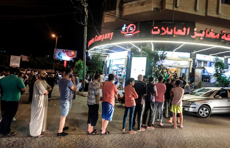 People queue outside a bakery following an announcement calling for the closure of public spaces across the Gaza City amid rising number of coronavirus cases.  AFP