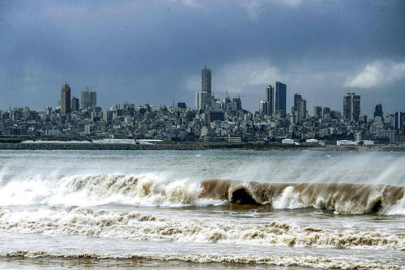 This picture taken on February 17, 2021 from the area of Dbayeh at the northern outskirts of the Lebanese capital Beirut shows waves crashing along the seashore during stormy weather with the Beirut skyline prominent in the background.  / AFP / JOSEPH EID
