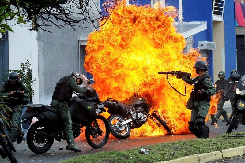 Riot security forces clash with demonstrators as a motorcycle is set on fire during a prostest in Venezuela. Carlos Eduardo Ramirez / Reuters