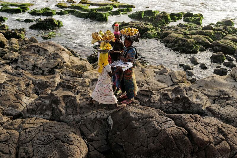 A group of girls look at a magazine as they carry fruit to sell in Dakar, Senegal. Reuters