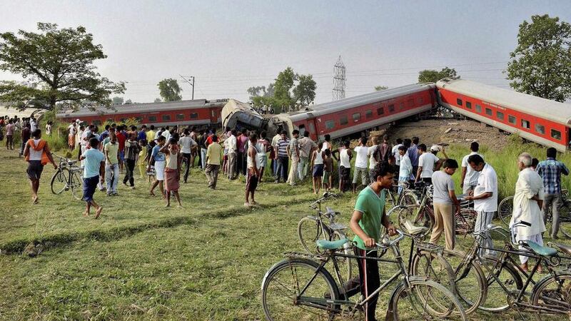 People gather around a passenger train that derailed near Chhapra town in Bihar, India on June 25, 2014. The cause of the accident was not immediately known, but officials say the incident killed at least four people and injured eight others. AP Photo