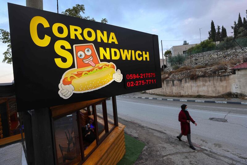 A woman walks past the "Corona Sandwich" restaurant in the occupied West Bank town of Bethlehem. AFP